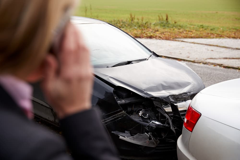 Female on phone reporting car crash in rural area of Georgia - seeking assistance after accident on a road.