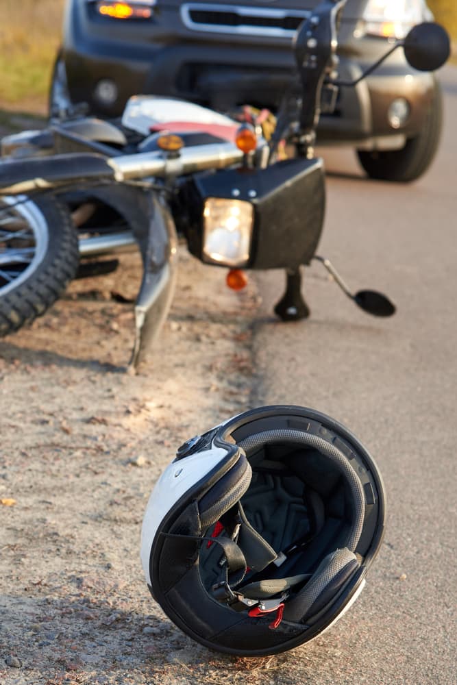 Image depicting a scene of potential road hazards with a car, helmet, and motorcycle on the road, emphasizing the concept of road safety and accidents.