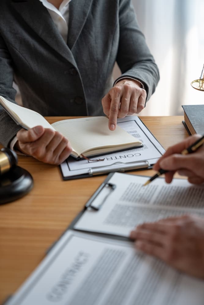 Legal professionals and businessman discussing agreement details, reviewing business contracts for accuracy, and strategizing joint financial investment.