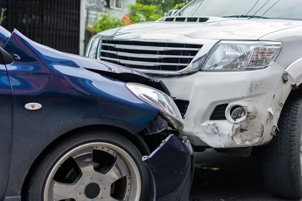 Collision between sedan and pickup truck on city road.