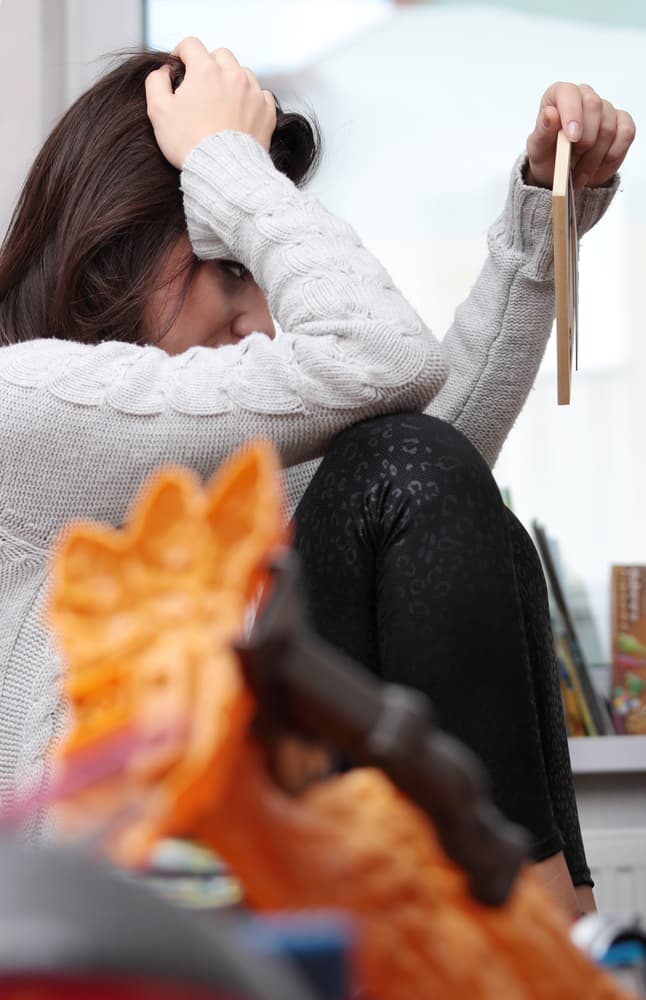 A sad woman sitting in room and looking on photo frame.