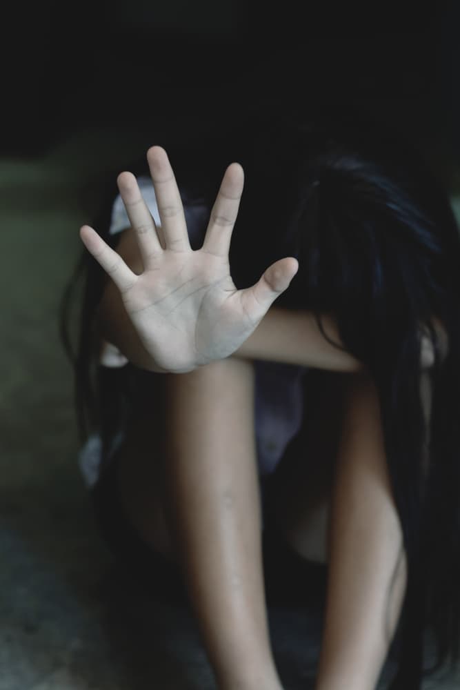 A distressed individual crouched down, reaching out, seeking help or to stop interaction, conveying a plea for aid.