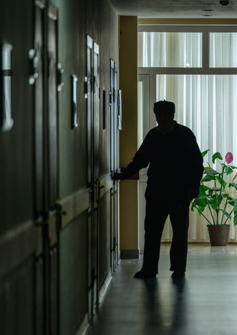 An older woman in a nursing home receiving care in a quiet, residential area.