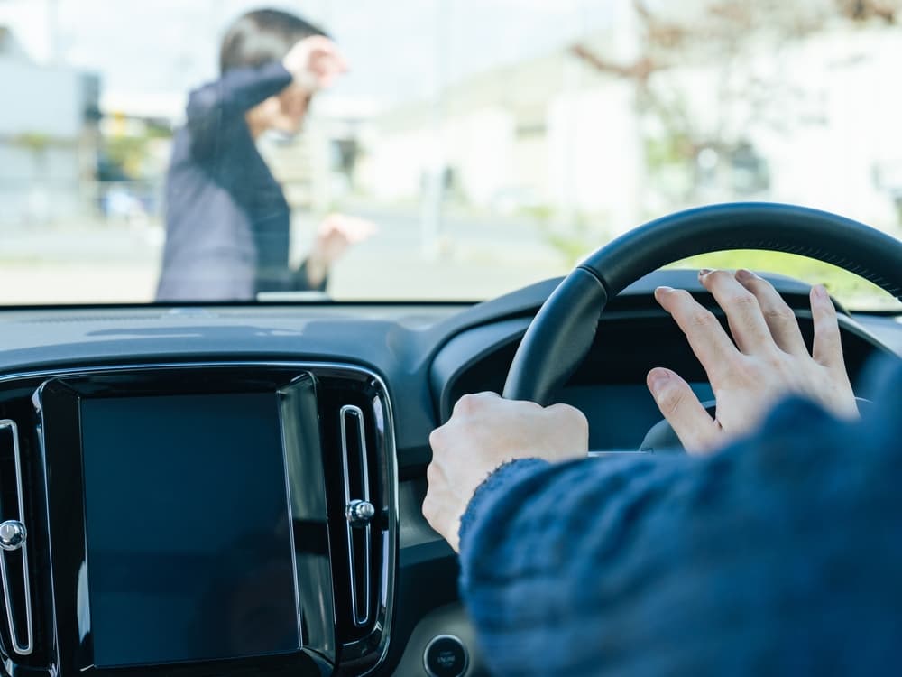 A driver honks at a woman as she crosses the street.